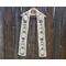 White scarf with snowmen along the length. It is on a hanger in front of a wooden fence.