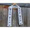Snowman scarf on a hanger in front of a wooden fence.