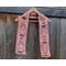 Display of the Balloon Crochet Scarf on a hanger in front of a wooden fence.
