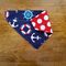 Over the collar dog bandana that is reversible from anchors to red with white polka dots.