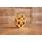 side view of a gold miniature movie reel magnet sitting on a wooden table