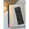 laminated bookmark on a book on a white table. Light brown table runner with fairy lights in a jar