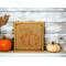 A rustic burlap wood sign with a oranged stenciled pumpkin on it.