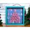 A small shadow box with a fa la la insert that has a wooden christmas tree that says a very merry holly jolly christmas attached.