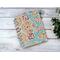 A blank handmade notebook with peach color lined paper that has a paisley cover