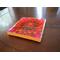 a close up of a pink and orange dahlia blossom on a coaster set on a dark wood coffee table