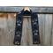 Black scarf with ghosts along the length. It is on a hanger in front of a wooden fence.