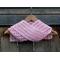 Display of the Shell Crochet Scarf on a hanger in front of a wooden fence.