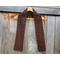 Display of the Grid Crochet Scarf on a hanger in front of a wooden fence.