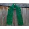 Dark green scarf with leaves along the length. It is on a hanger in front of a wooden fence.