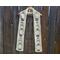 White scarf with snowmen along the length. It is on a hanger in front of a wooden fence.