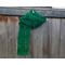 Another pic of the Leaf Crochet Scarf in green on a hanger in front of a wooden fence.