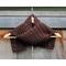Display of the Grid Crochet Scarf on a hanger in front of a wooden fence.