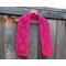 Display of the Diamond Crochet Scarf on a hanger in front of a wooden fence.