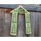 Display of the Tree Crochet Scarf on a hanger in front of a wooden fence.