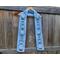 Display of the Snowman Crochet Scarf pattern on a hanger in front of a wooden fence.