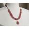Necklace with pink quartz pendant with pink quartz nuggets, cream colored shell beads, and tiny red garnet beads with gold hook clasp