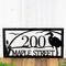 Close up of rectangular metal address sign with great blue heron, cattails, and and sunset lake scene, in matte black powder coat.