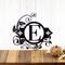 Metal monogram sign with fleur de lis and vines, in matte black powder coat.