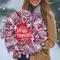 Woman holding rustic holiday wreath with red and white ribbons, glitter snowflakes, and festive farmhouse Christmas accents.