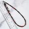 Black and red beaded choker necklace next to a ruler.