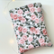 This floral book sleeve has a white background with pink flowers and dark green leaves