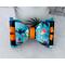Close up of teal & black Halloween print hair bow with loops of orange ribbon. 4 layers total. Bow is sold individually. 