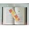 this laminated book mark is in the middle of an open book with fairy lights around the book on a white table