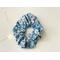 this blue floral scrunchie has a blue background with some blue flowers. The flowers are small in colors light pink and blue