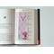 this laminated bookmark is on top of an open book on a white table