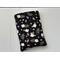this floral book sleeve has a black background with white flowers and green and purple leaves