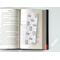 the laminated bookmark is on top of an open book on a white table