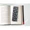 the laminated bookmark is on top of an open book