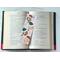 this ornament book mark is in the middle of an open book with fairy lights above the book