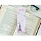 Eiffel Tower book mark is on top of an open book with a pair of glasses above the book on a white table