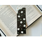 this floral bookmark has a black background with white flowers and green leaves and hearts all over the page holder.