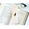 this cat page saver is on top of an open book with a pair of glasses on a white table
