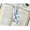 the Paris book mark is on top of an open book with a pair of glasses on a white table