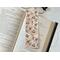 this rustic bookmark is on top of an open book with a pair of glasses peeking from the top with fairy lights on the right side of the book