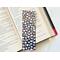 this floral bookmark has a navy blue background with small white polka dots & flowers (white, orange, yellow, pink, purple) and bees all over the bookmark