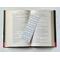 the elegant bookmark is in the middle of an open book with fairy lights around the book on a white table
