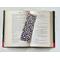 the laminated bookmark is in the middle of an open book with fairy lights around the book on a white table
