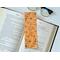 the flower bookmark is on top of an open book with a pair of glasses on a white table above the book