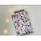 an ereader is peeking out of the floral kindle cover on a white table an with fairy lights on the left side