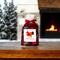 Handmade apple cinnamon potpourri displayed on a wooden table, with a fireplace and a snow-covered pine tree blurred in the background.