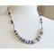 necklace with 1/2" in diameter white and purple shell button style beads, smaller faceted charoite gemstones, and a stainless steel chain 