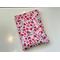 this floral book sleeve has a white background with tiny red and pink flowers and hearts all over it