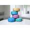 Stack of NMJ shampoo bars in gold, teal, pink, and blue, perfect for eco-conscious hair care.