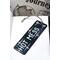 Front of bookmark, black background with handwritten white lettering and various white/hot pink dot art around the edges.  Jute rope tassel.