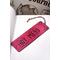 Front of bookmark, hot pink background, black handwritten lettering, black and white dot art designs around edge.  Jute rope tassel.